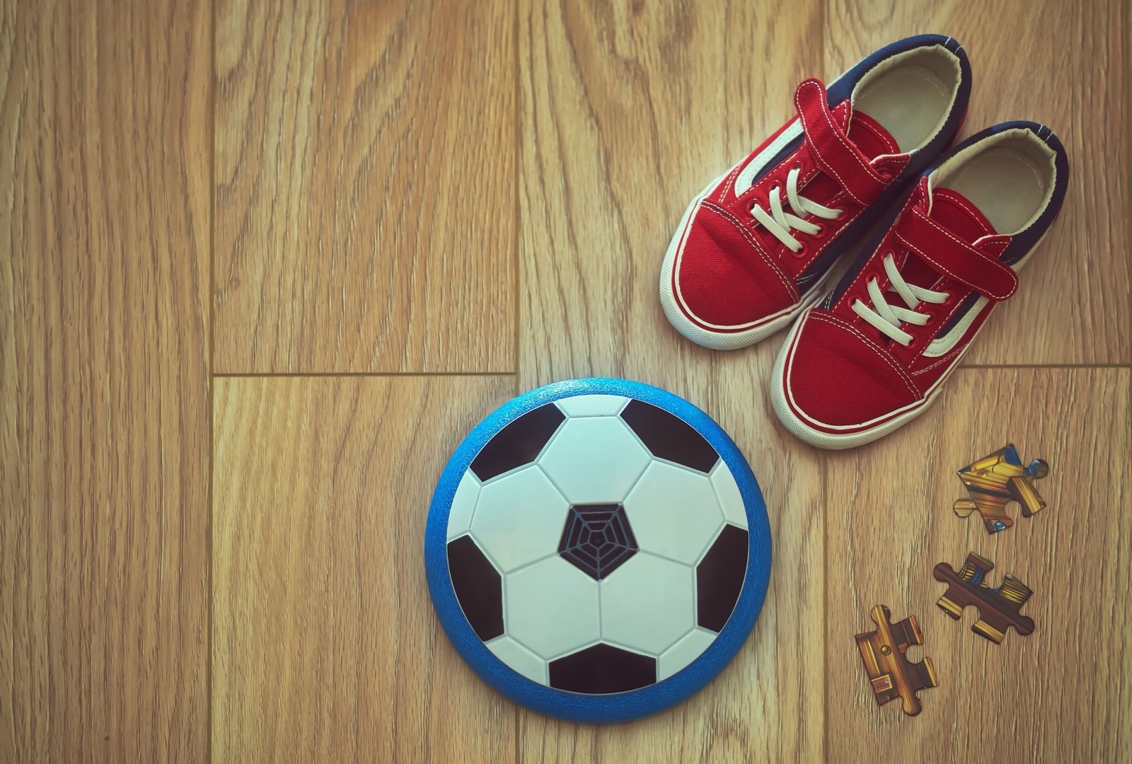 Kinderturnschuhe und Ball auf einem Holzboden
