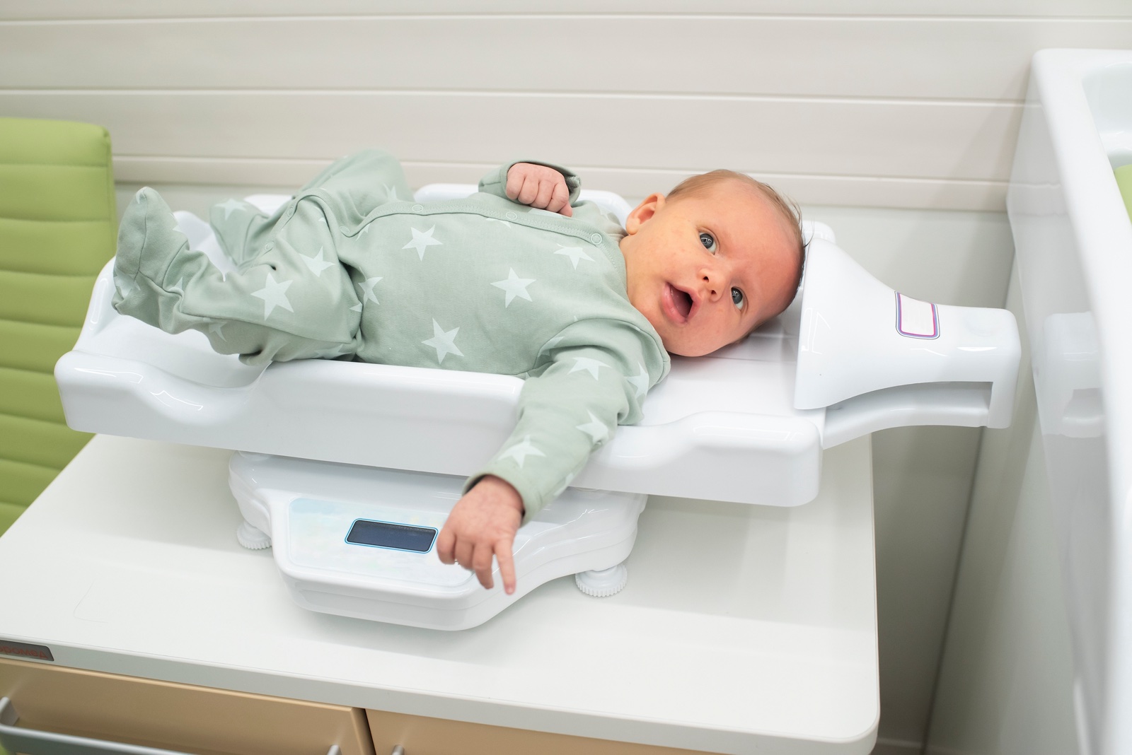 Säugling im Alter von etwa einem Monat liegt auf einer Babywaage