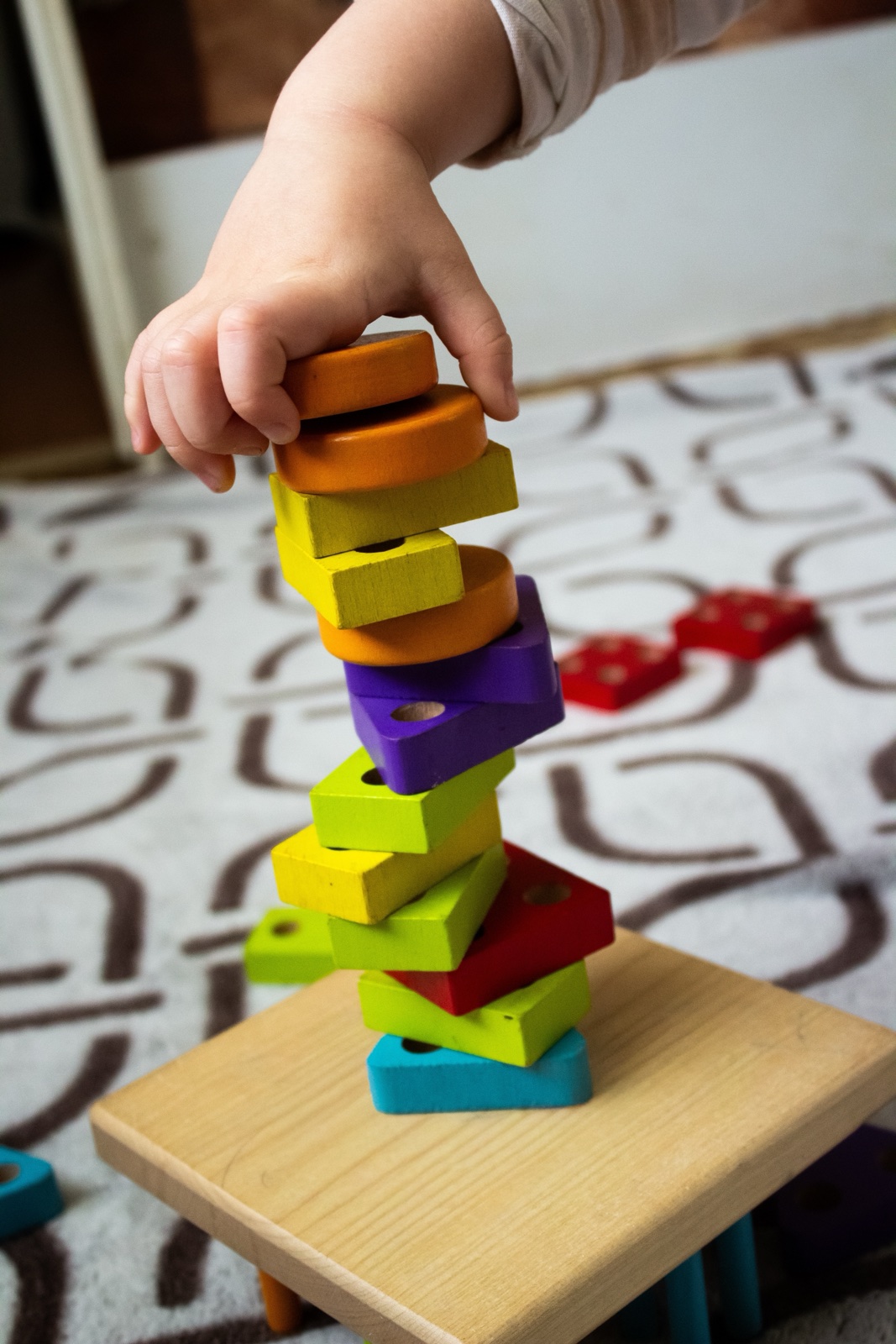 Kinderhand stapelt bunte Holzklötze zu einem Turm