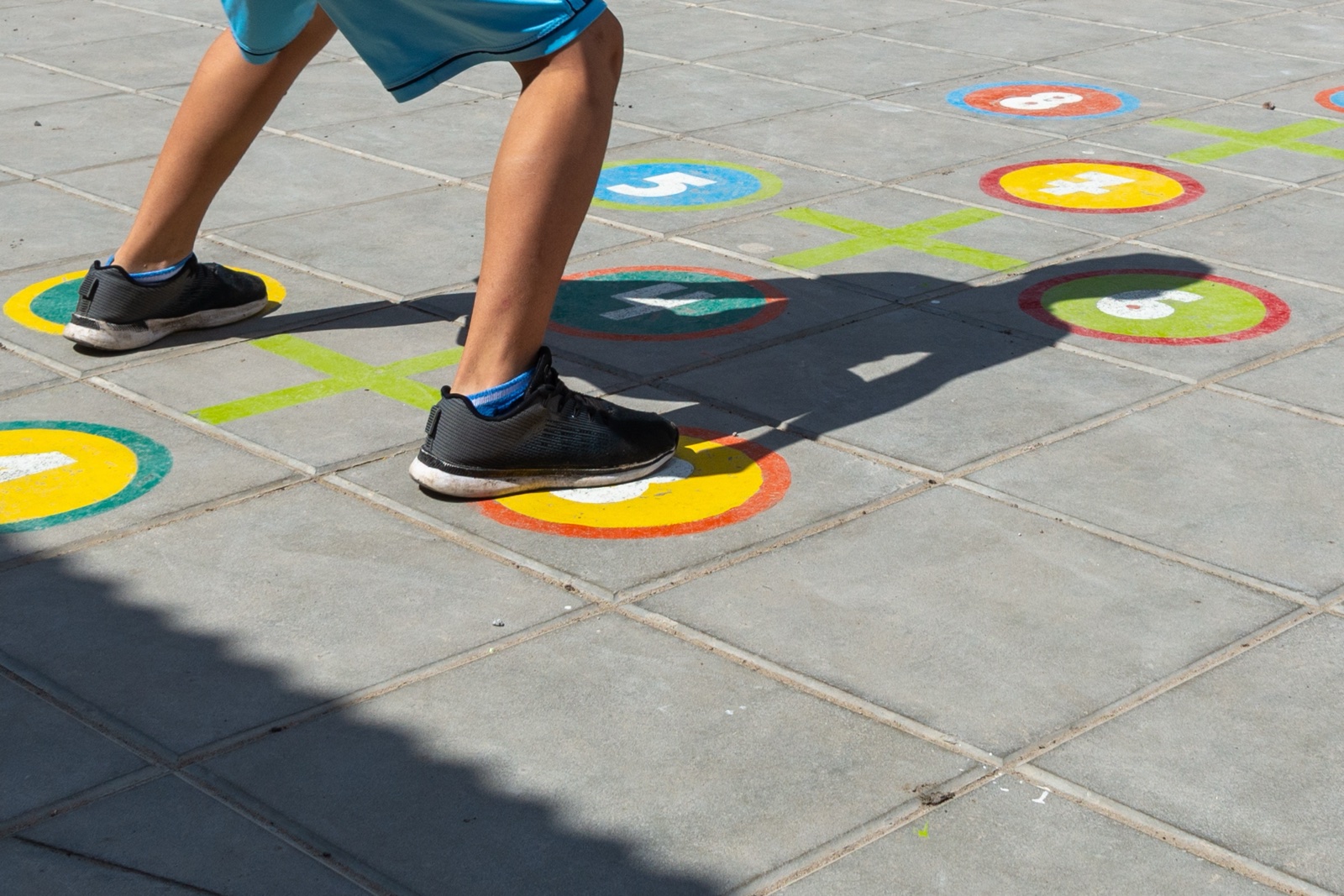 Kinderbeine beim Hüpfspiel auf bemaltem Pflaster