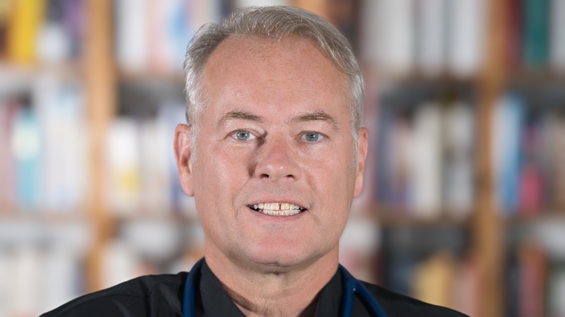 Dr. Wolfgang Stock vor einer Bücherwand